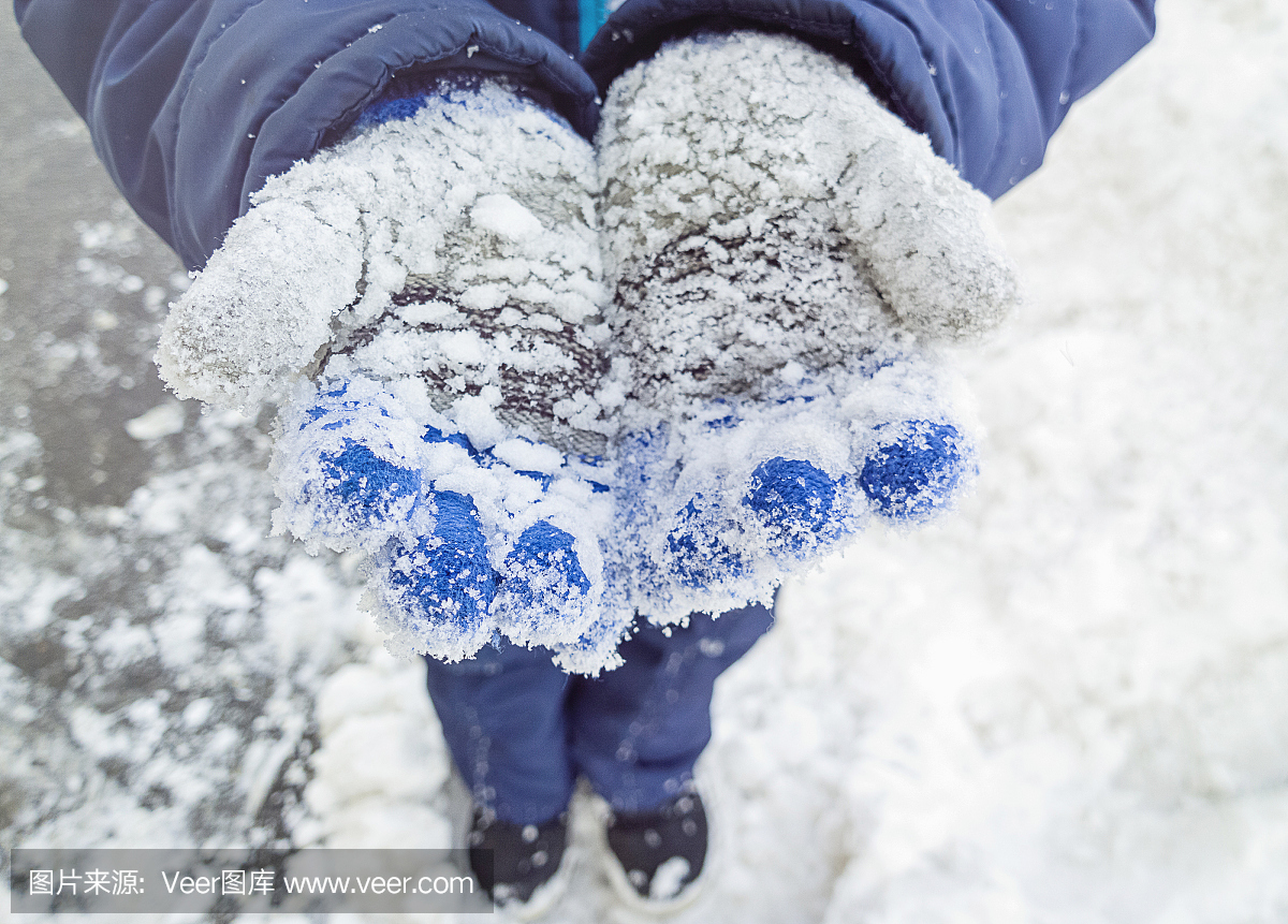 一个在雪地里戴着针织手套的小孩。裁剪后的图