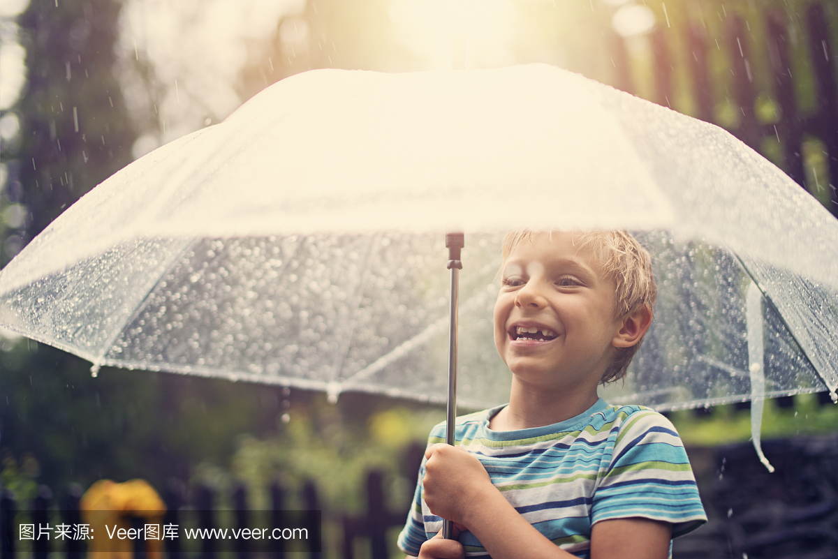 享受春雨的透明伞的小男孩。