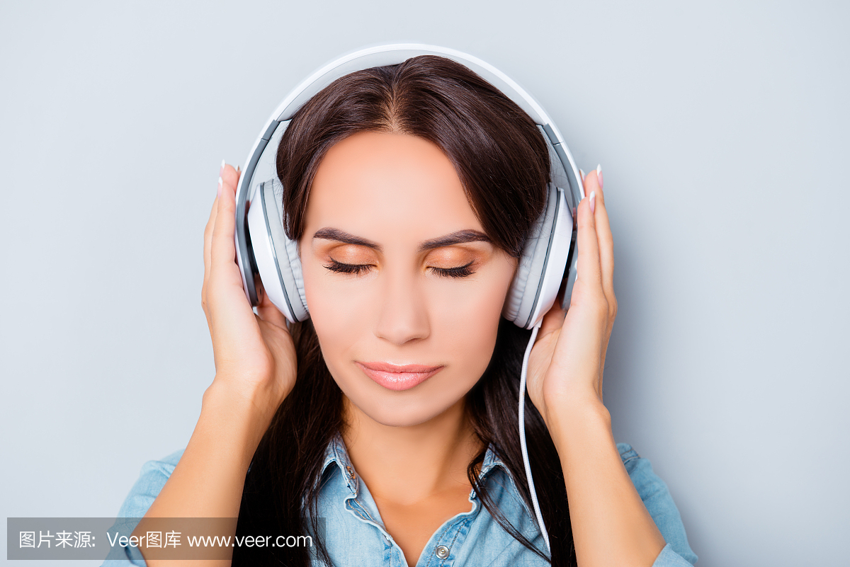 平静的女人在闭着眼睛的耳机听音乐的画像