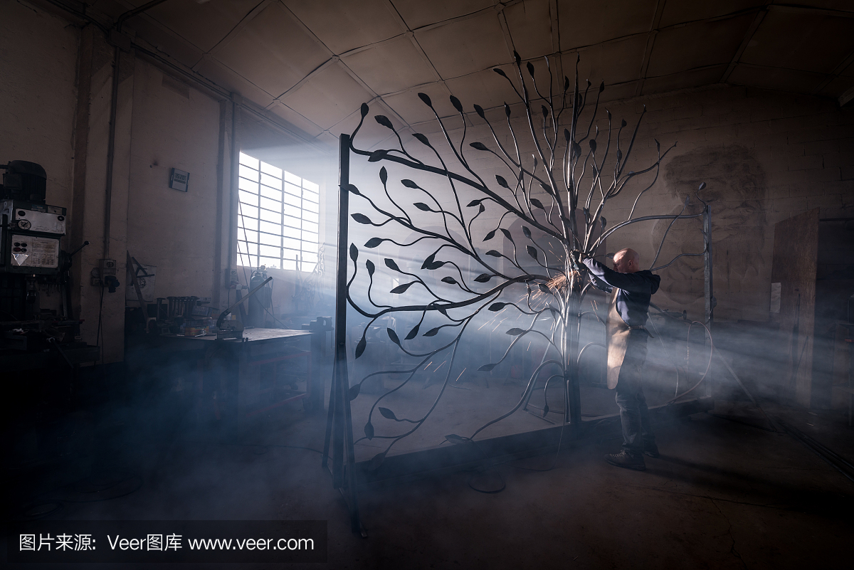 铁匠艺术家在他的铁匠铺工作,创造一个门树