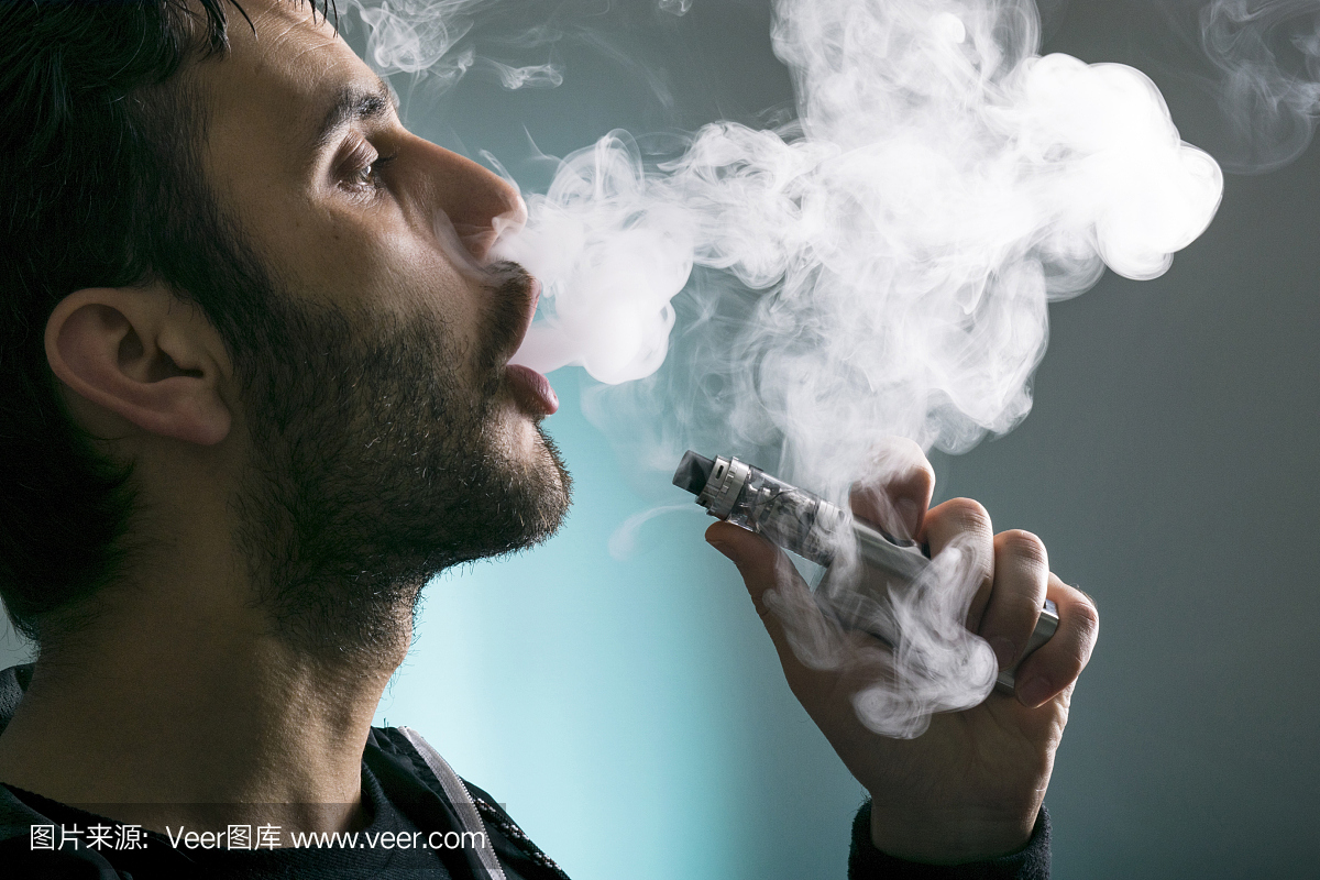 年轻男子vape电子香烟云使用mod,烟雾技巧的