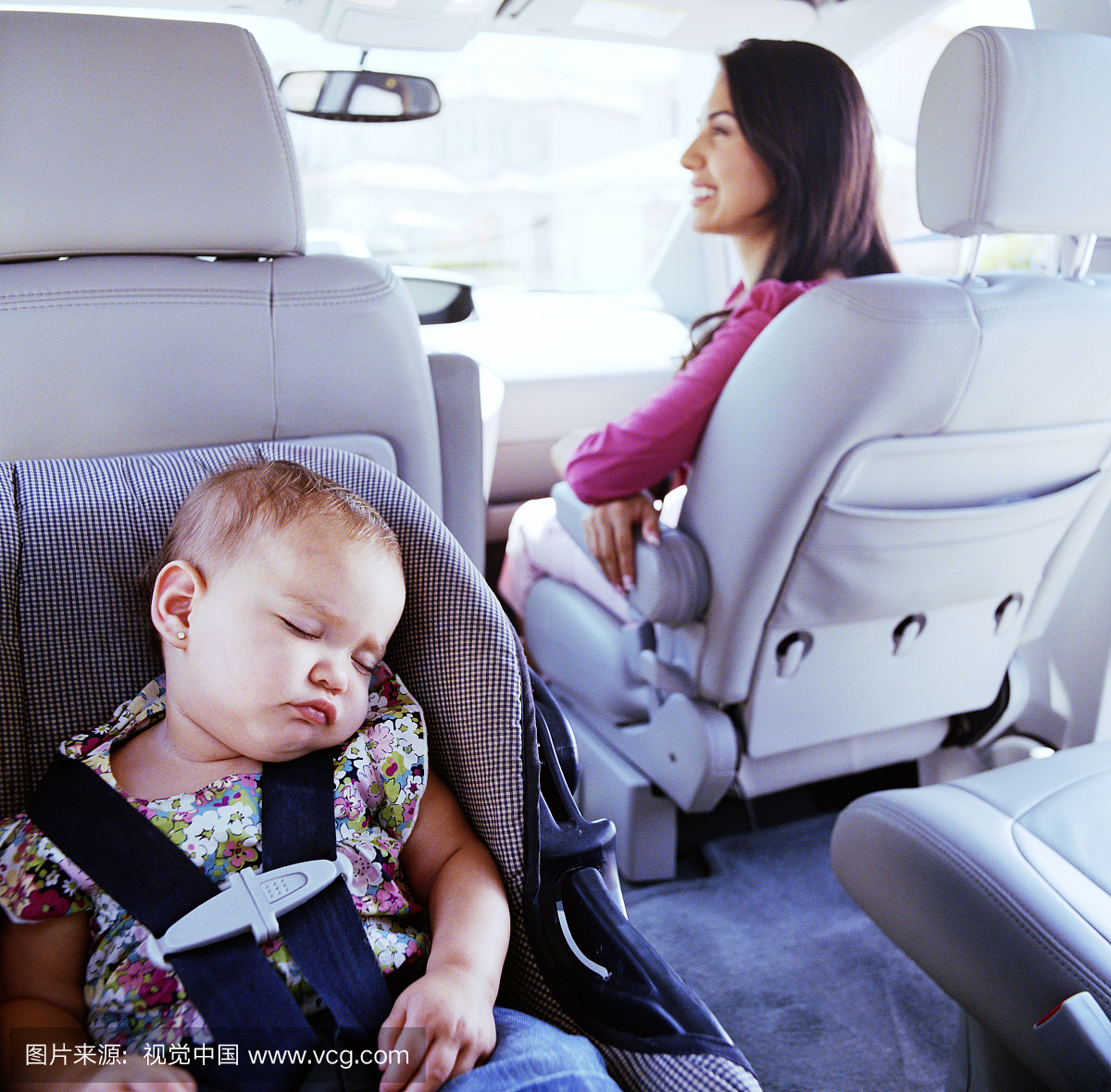 婴儿(12-15个月)睡在汽车座椅,女人在背景中