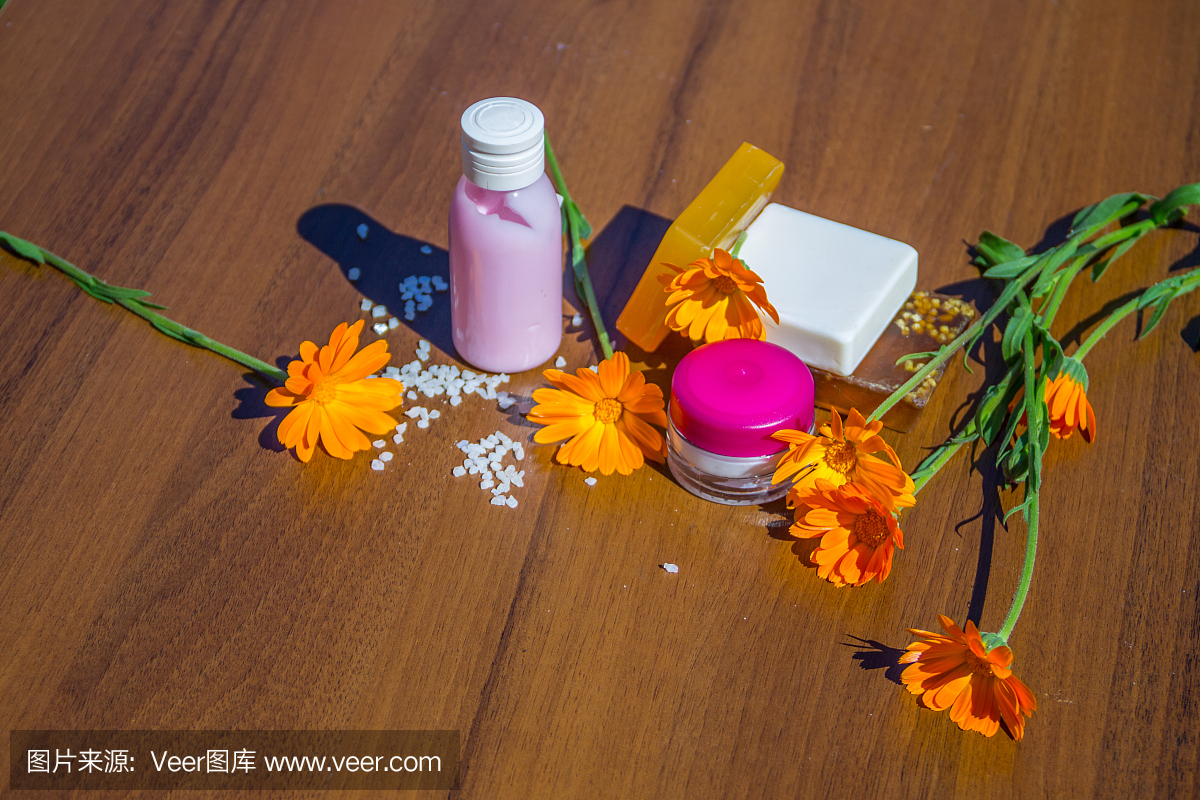 美容治疗产品和金盏花在木背景上。水疗套装