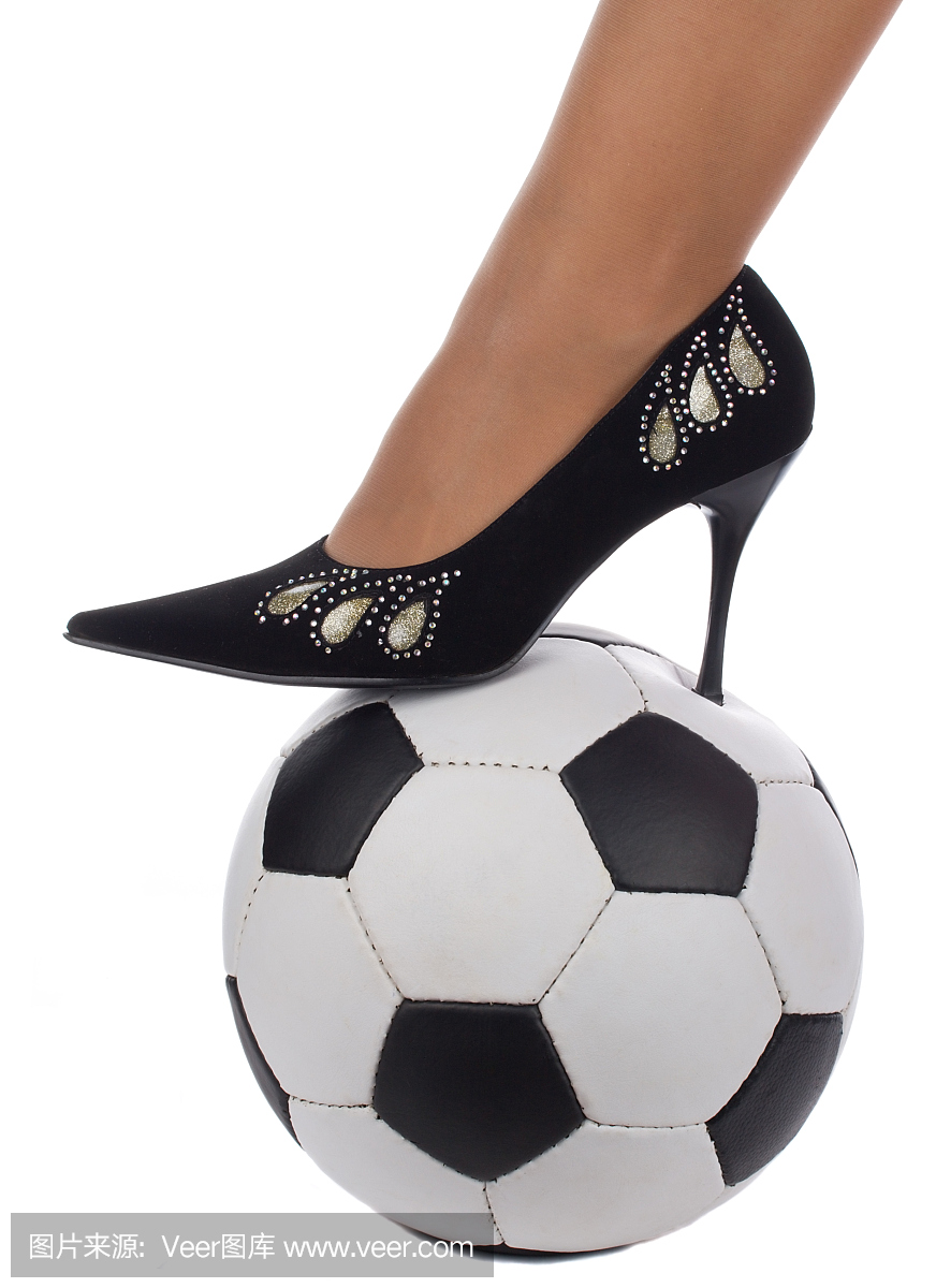高跟鞋的女脚站在足球上
