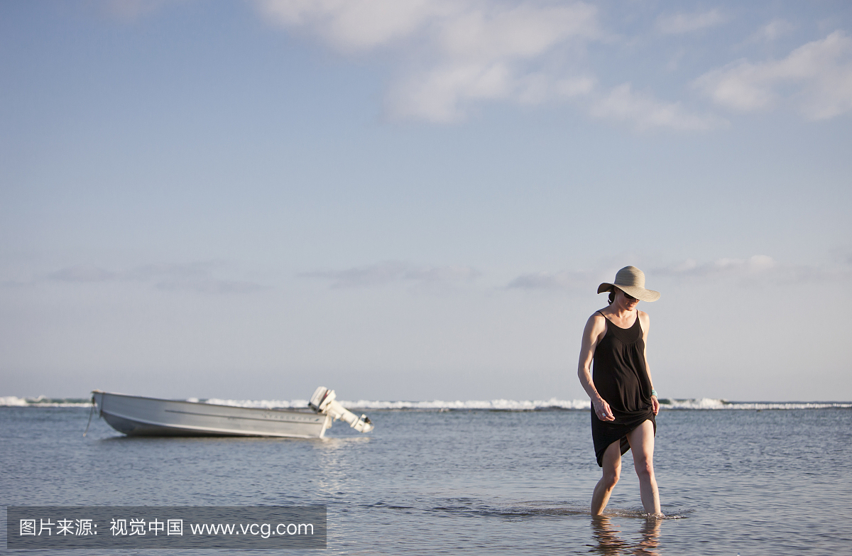 女人从热带的一条小船走到岸边