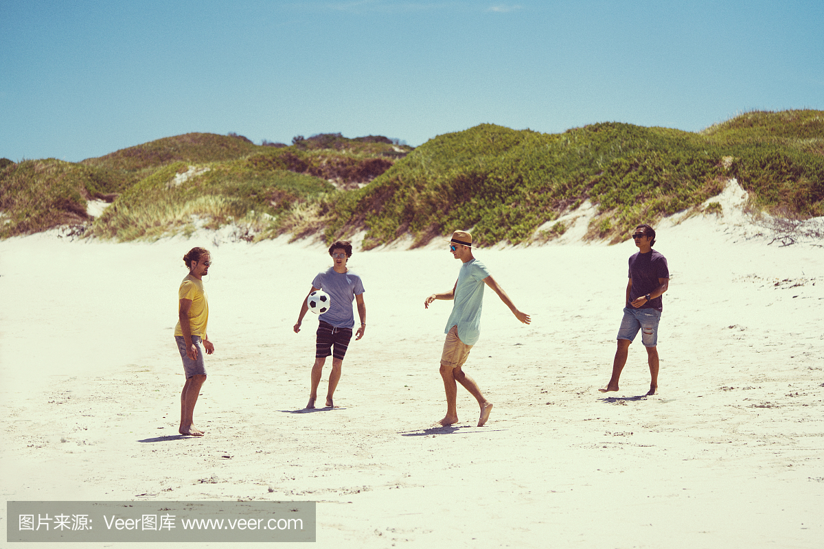 年轻的男性朋友在岸上踢足球