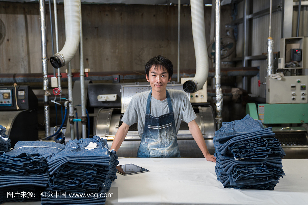 自信的纺织工业工人用数字平板电脑分拣服装