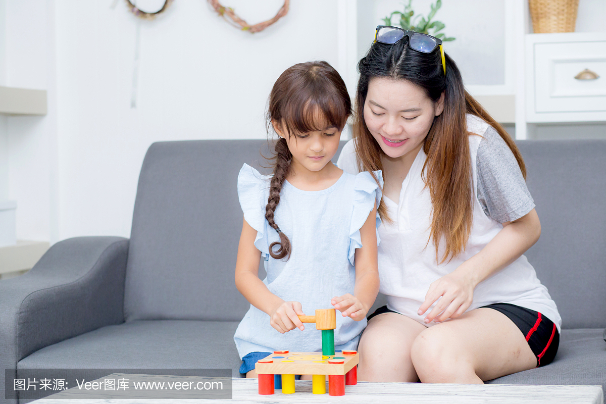 亚洲孩子女孩和母亲玩玩具积木;一起在客厅里