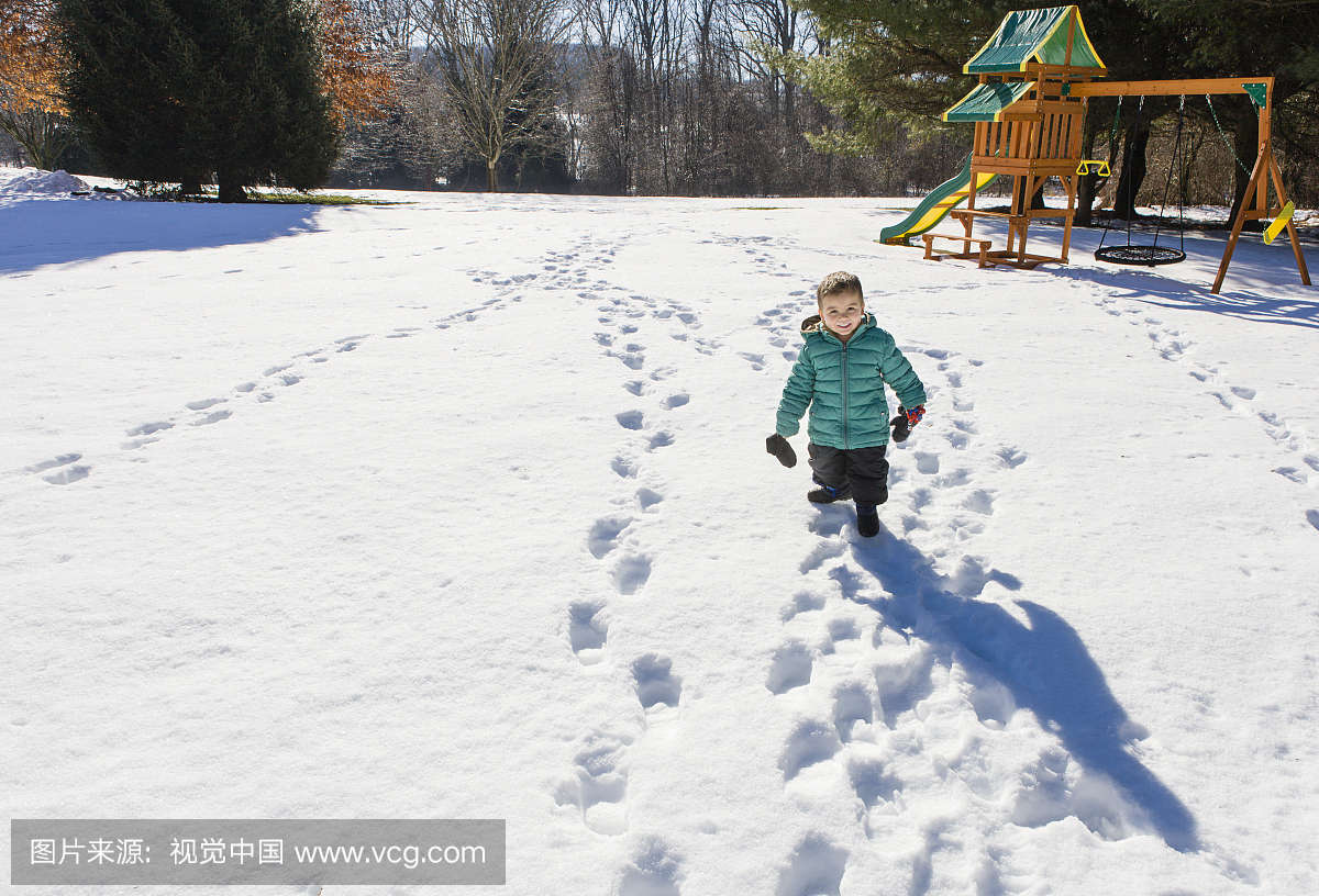 学龄前的男孩在雪地上行走的高角度视图