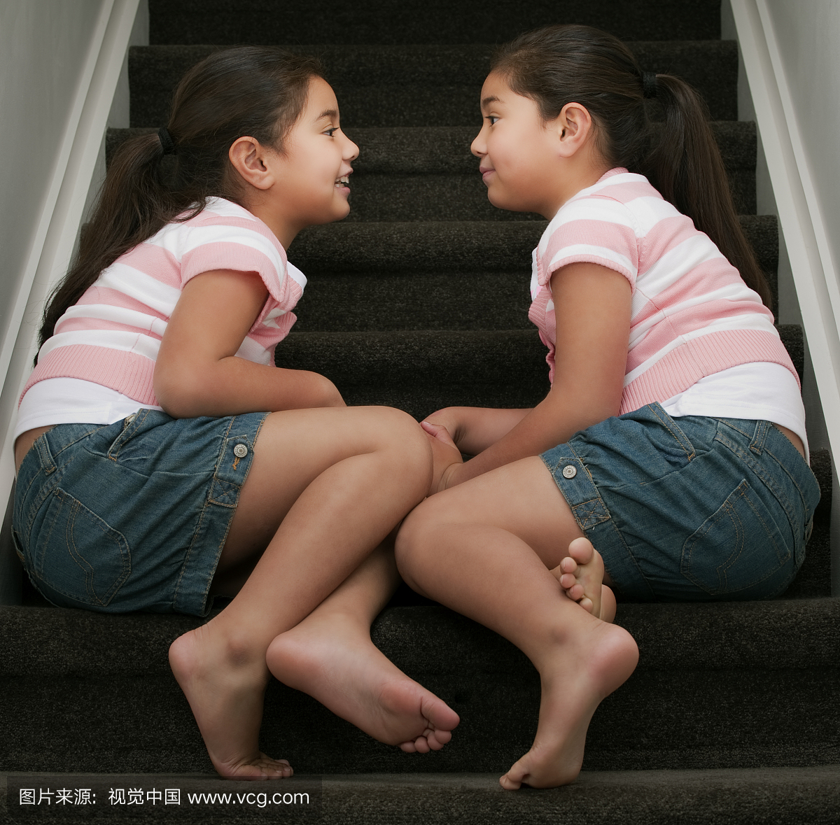 双胞胎姐妹坐在楼梯上,说话。