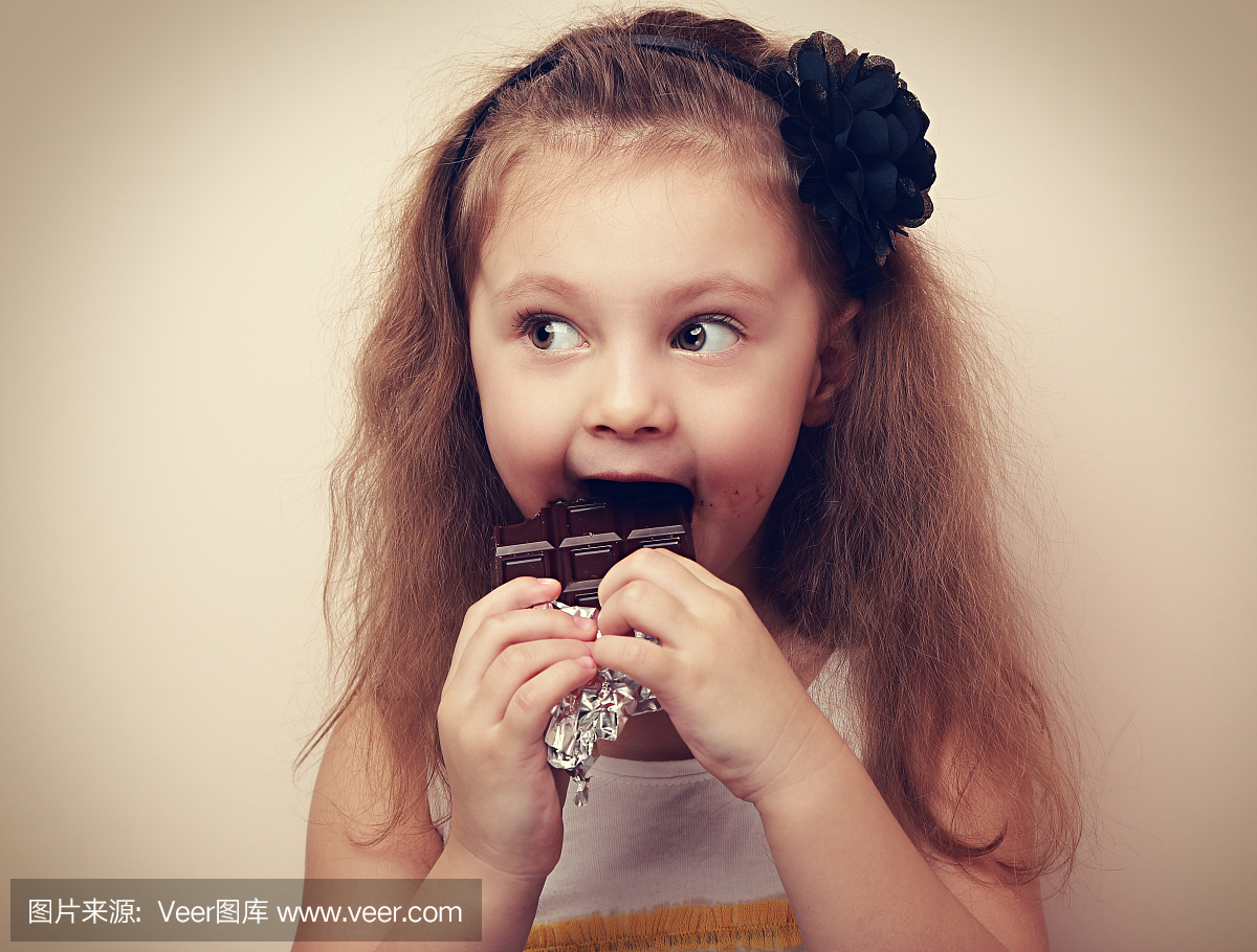 有趣的孩子吃黑巧克力的小女孩。葡萄酒特写