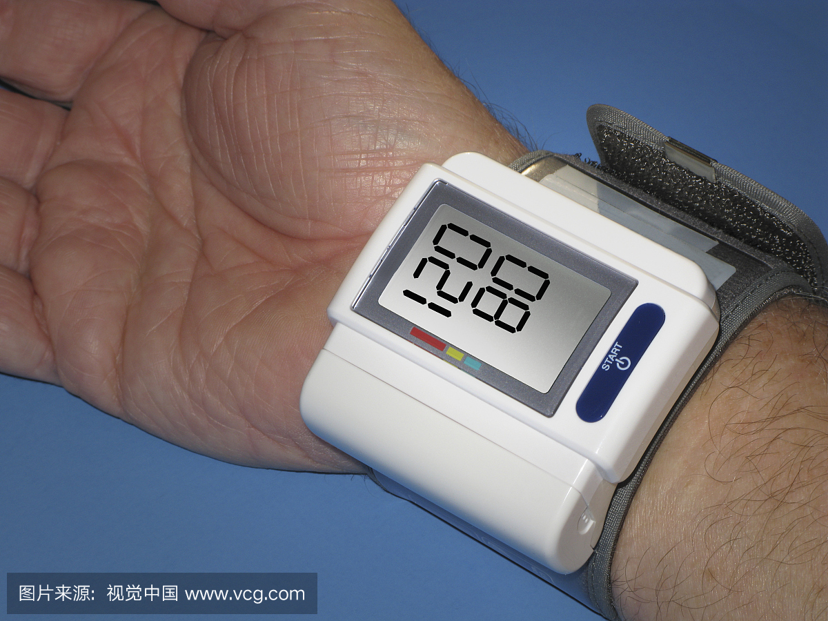 一名成年男子手戴腕带测量血压。数字在正常范