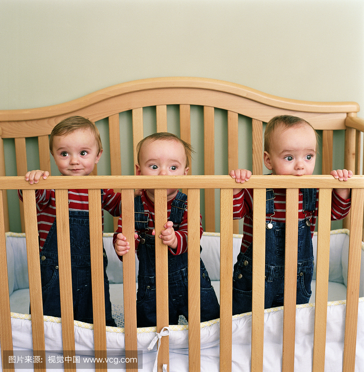 三重婴儿(9-12个月)站在婴儿床