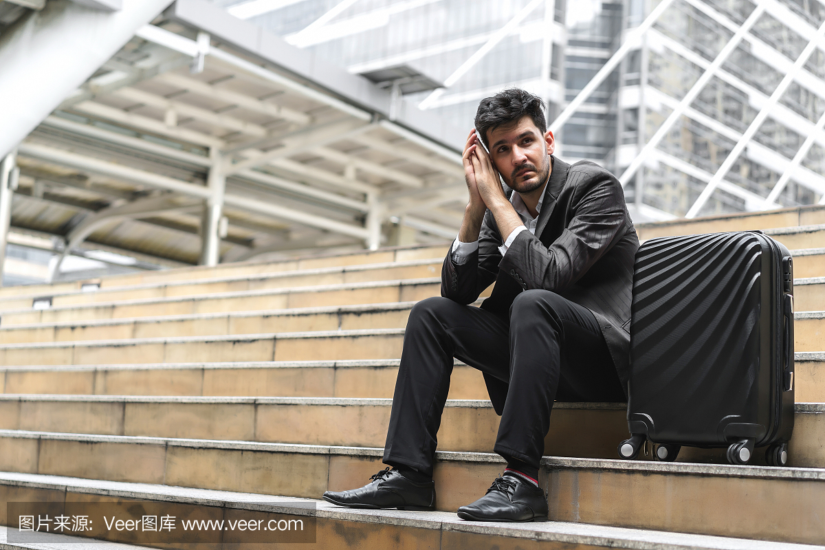 坐在楼梯与行李的商人在与决心和信心一起使用