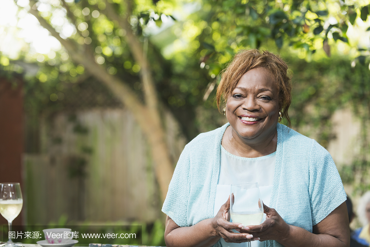 高级非裔美国人的女人与一杯白葡萄酒