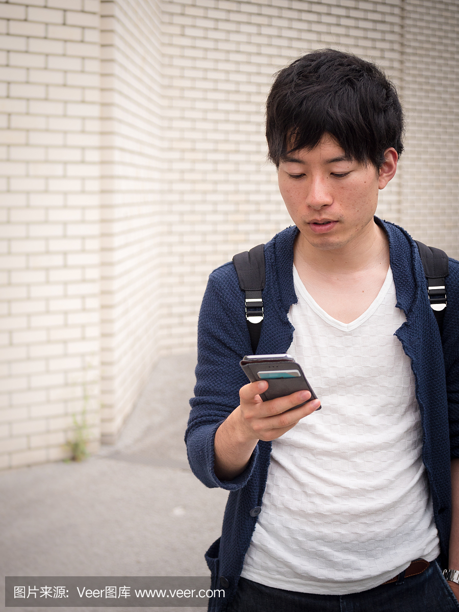 年轻的日本学生发短信给他的智能手机