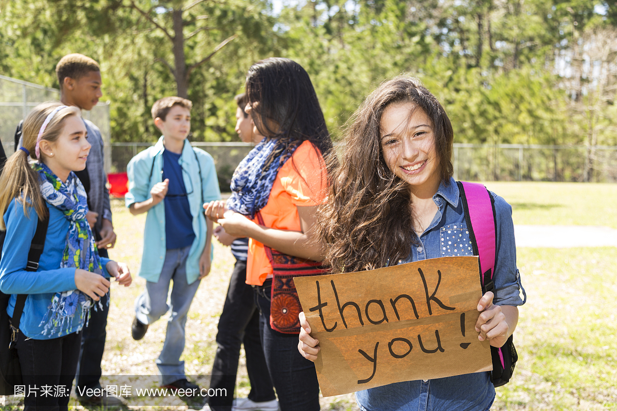青少年拉丁女孩抱着谢谢登录公园。