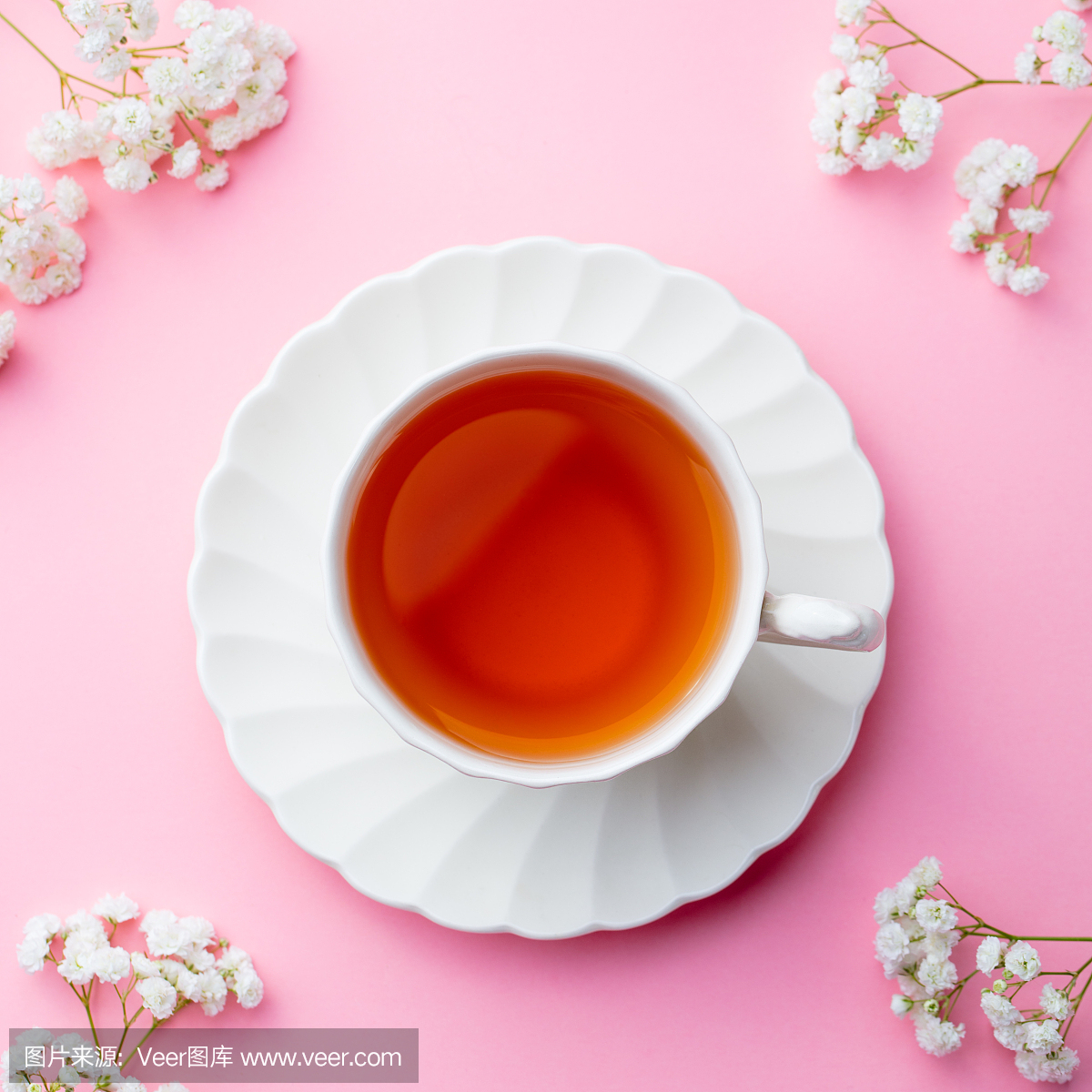 喝杯茶与粉红色的背景上的鲜花。顶视图。复制