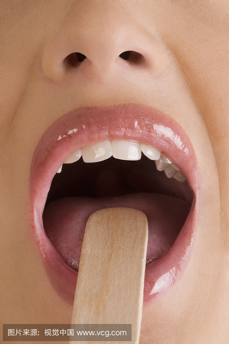 一个年轻女子使用舌头抑郁症检查她的舌头的特