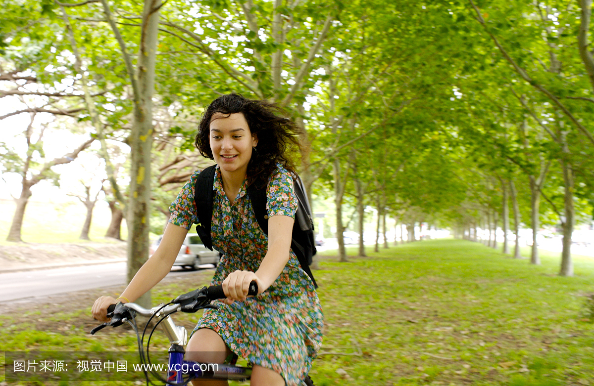 年轻女子骑自行车穿过树林大道,牛津街。