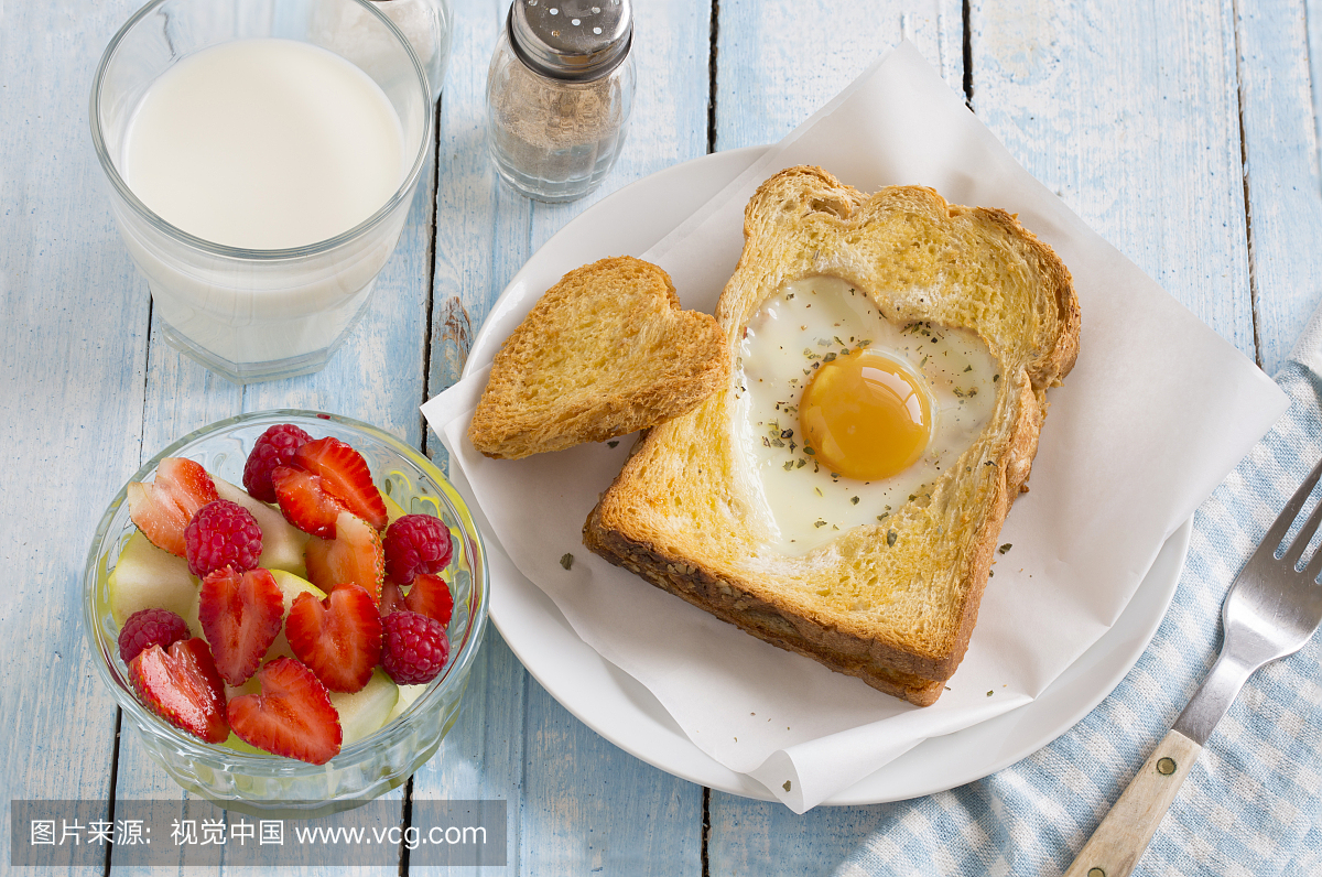 Heart shaped sunny side egg with toast on woo