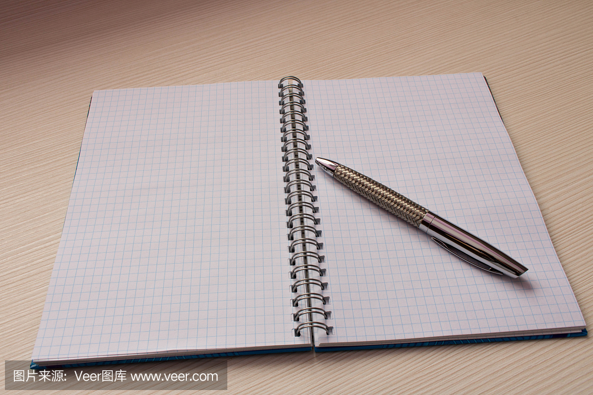 一支笔和一张记事本在桌子上。笔记本打开