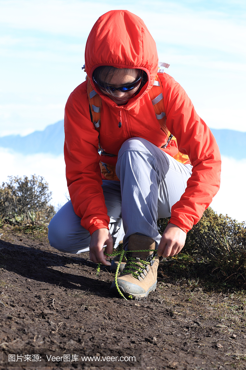 徒步旅行者徒步旅行者在美丽的山峰上绑鞋带