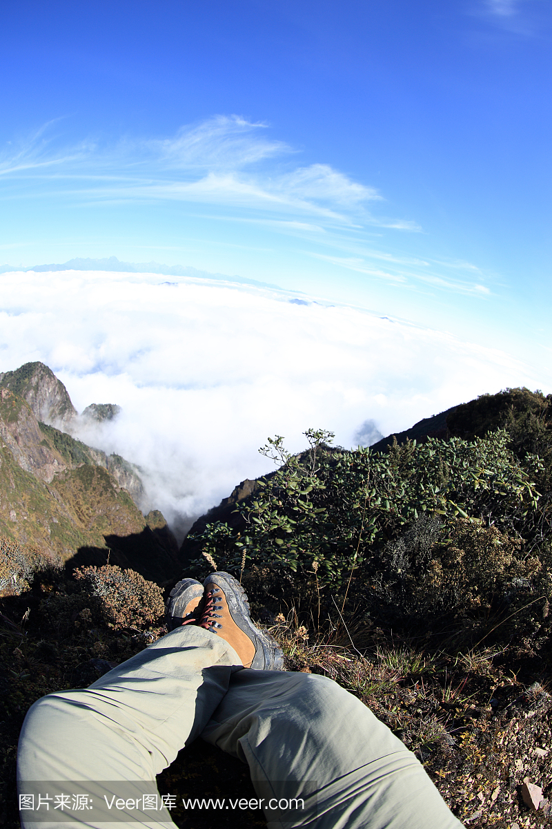 年轻女子徒步旅行者坐在美丽的山峰上