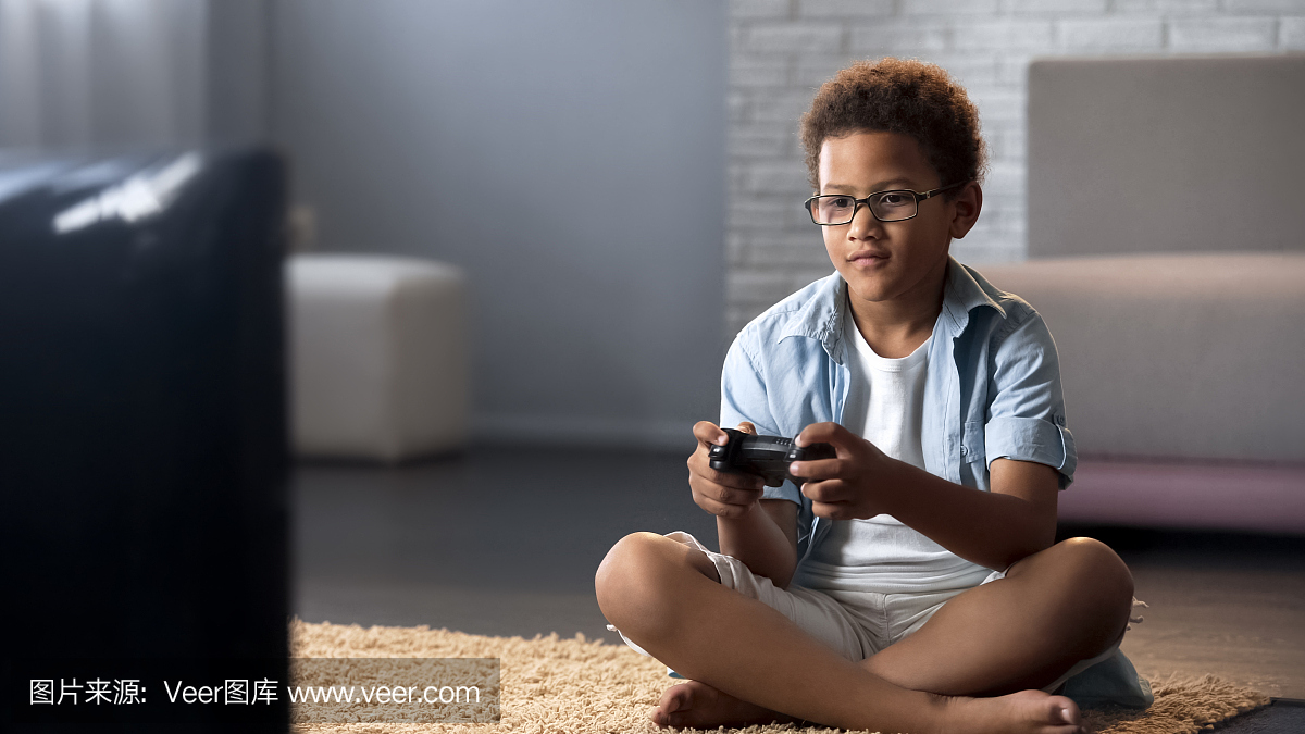 美国黑人男孩花费他的空闲时间在游戏机上玩游