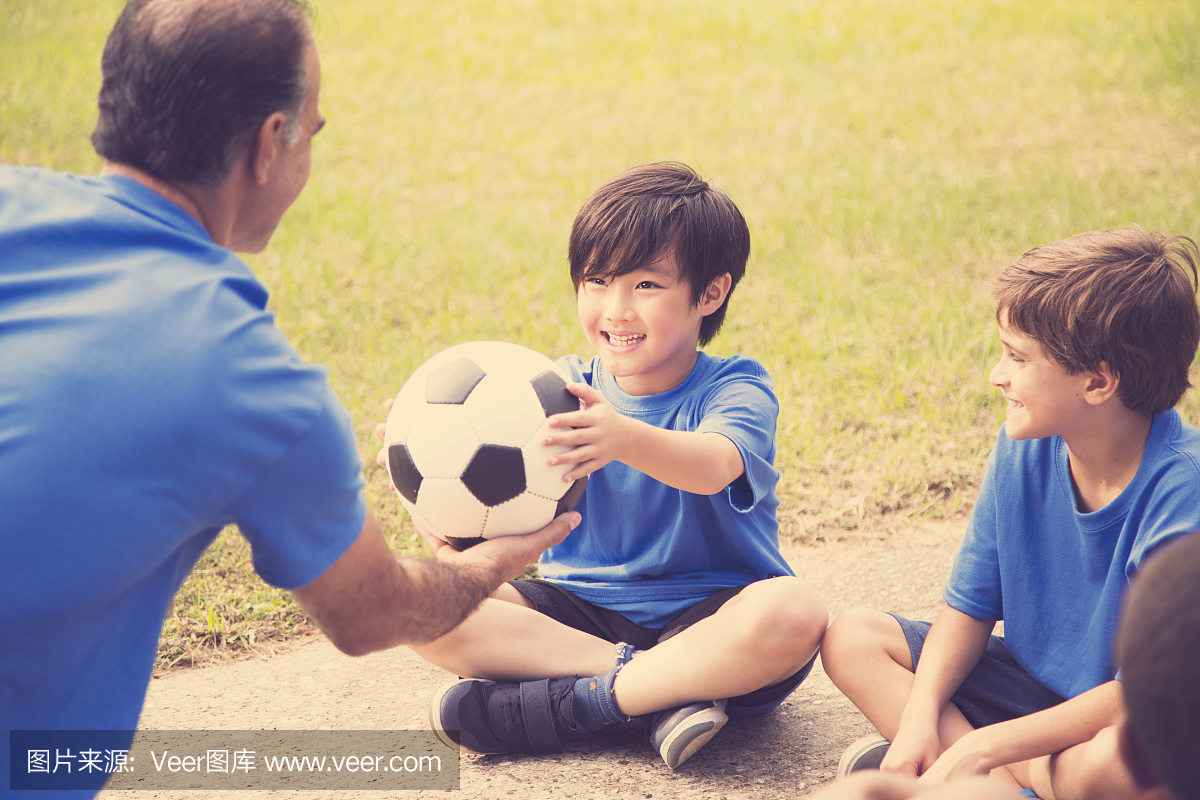 儿童足球队教练将球给对手。