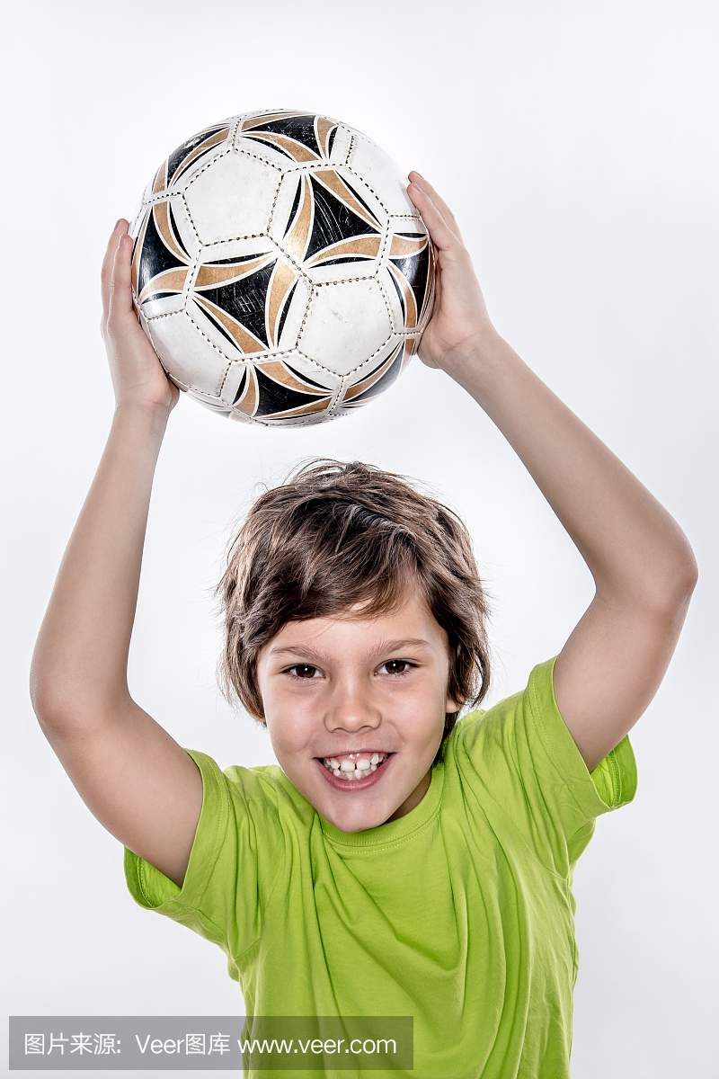 逗人喜爱的微笑足球孩子举起足球在头上