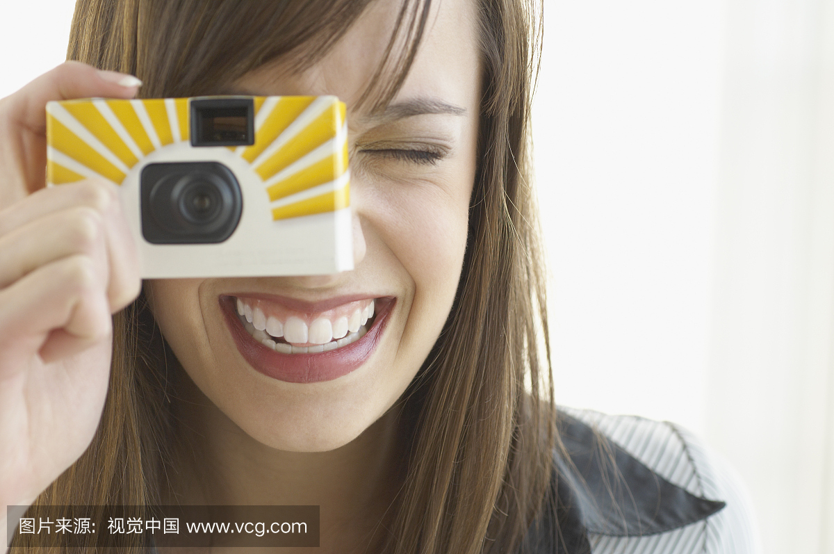 用一次性相机拍照的年轻女子,微笑