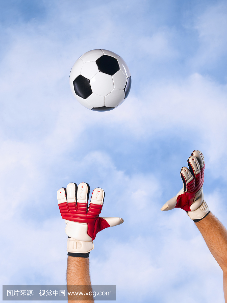 守门员抓住对天空的足球,手臂和手的特写
