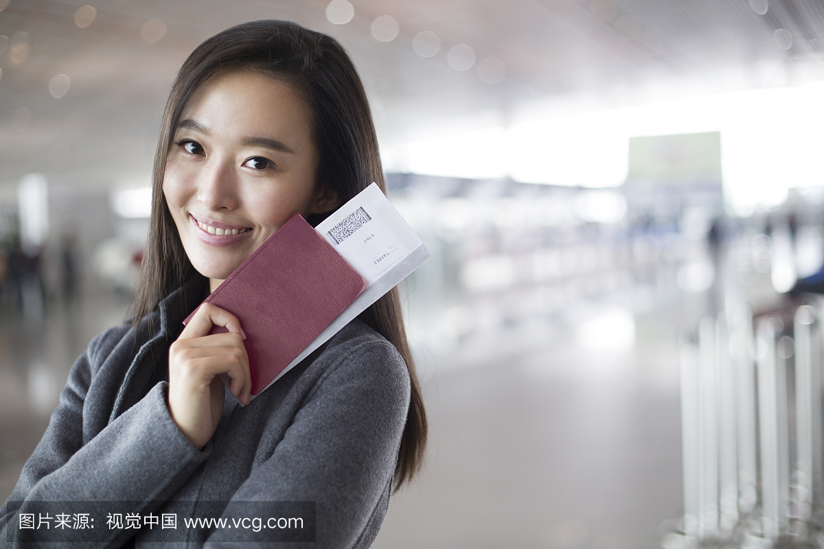 年轻商务女子在机场拿着机票和护照