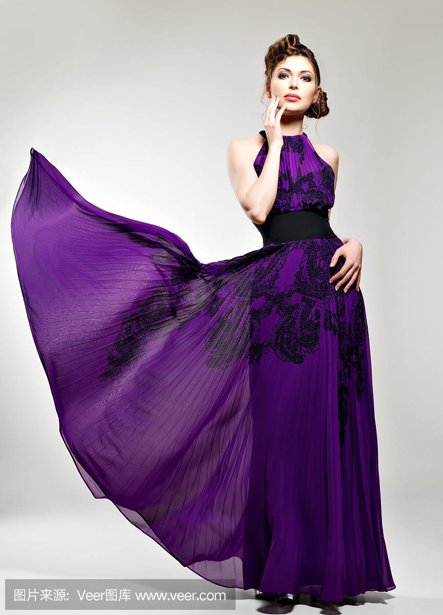 美丽的时尚女人在紫色长的连衣裙