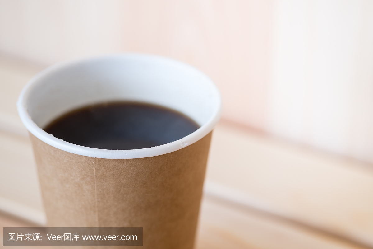 关闭热的黑咖啡美式纸杯在木桌上。