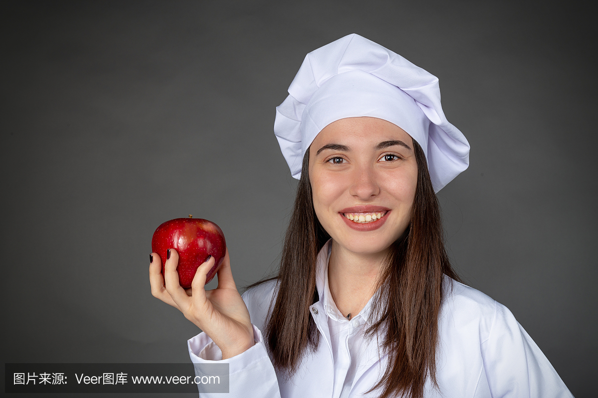 美丽的土耳其年轻女厨师在她的手上保持一个苹