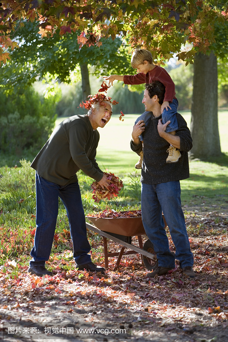 老人在花园里收集秋叶,父亲的肩膀上孙子,爷爷