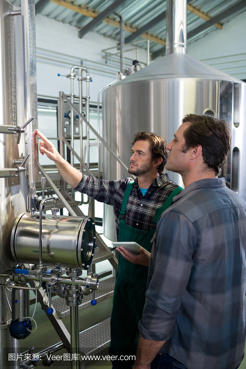 拿着平板电脑的工作者解释对工友