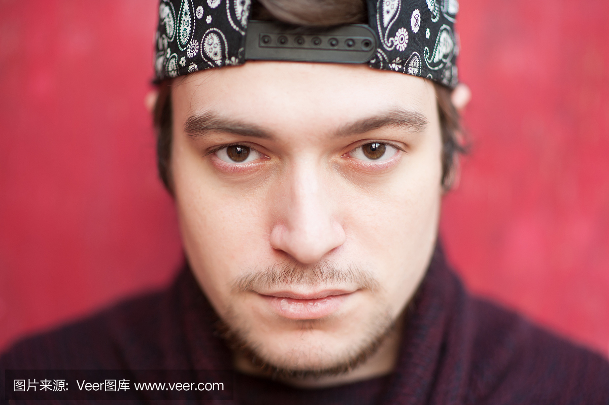 一名英俊的年轻男子在一个棒球帽和一件红色背