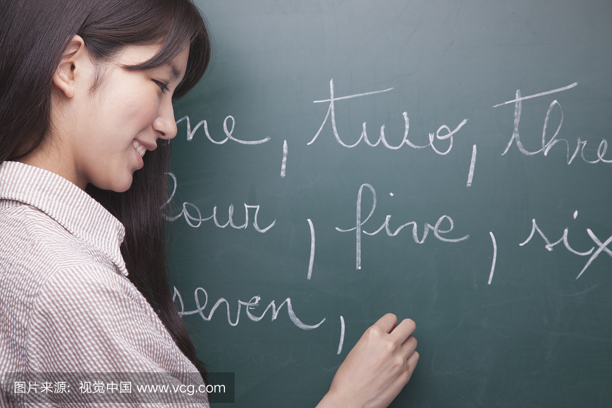 在黑板上写英文数字的年轻女子学生
