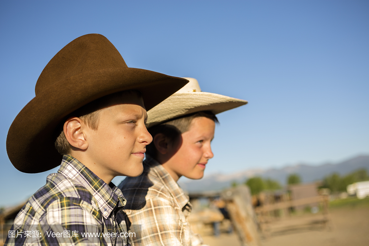 牛仔:儿童。男孩在家伙牧场,山脉,畜栏。