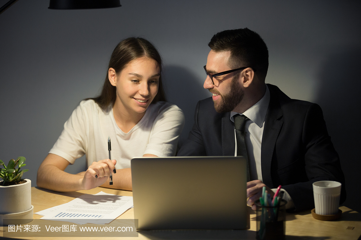 微笑愉快的商业伙伴讨论在夜班工作项目