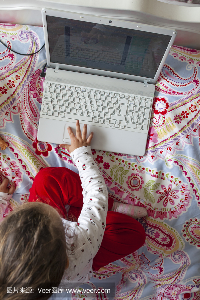 小女孩坐在床上玩网络游戏