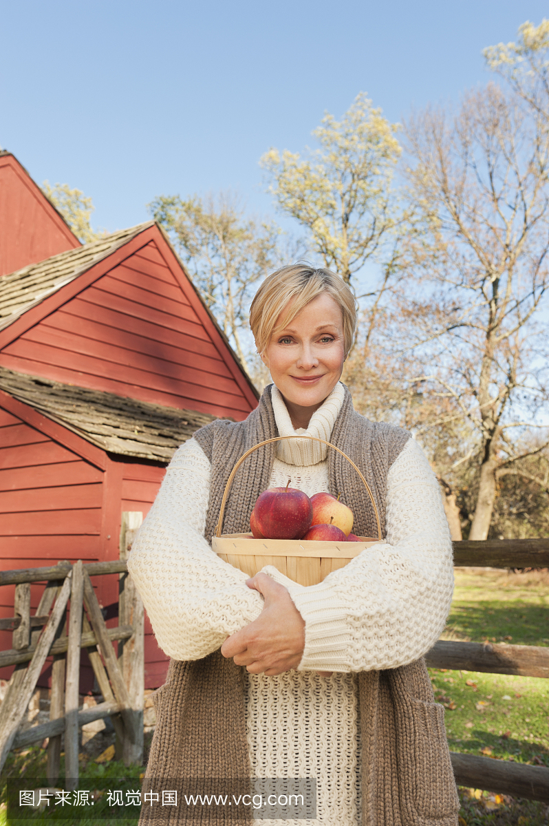 美国,新泽西州,肖像的微笑的女人拿着篮子与苹