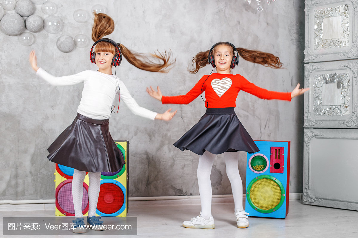 快乐的孩子们跳舞,并听音乐的耳机。这个概念