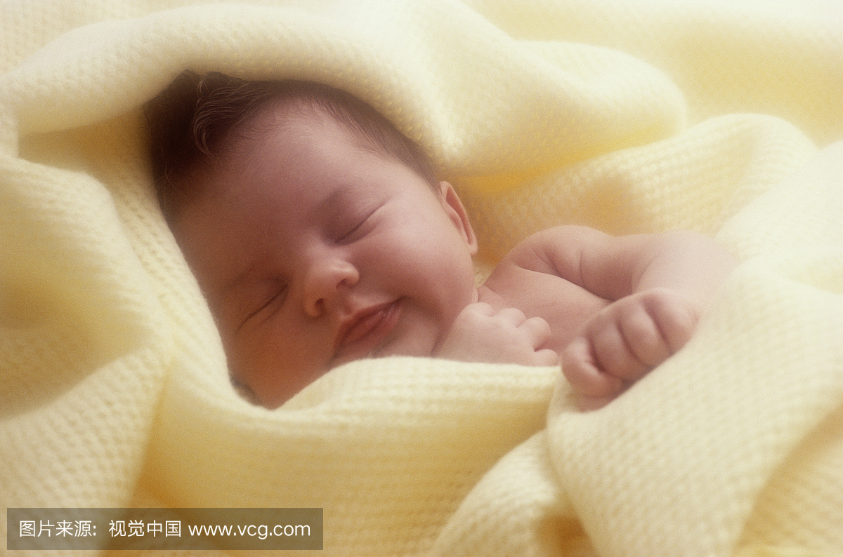 宝贝女孩(0-3个月)睡觉,裹着黄色的毯子,特写