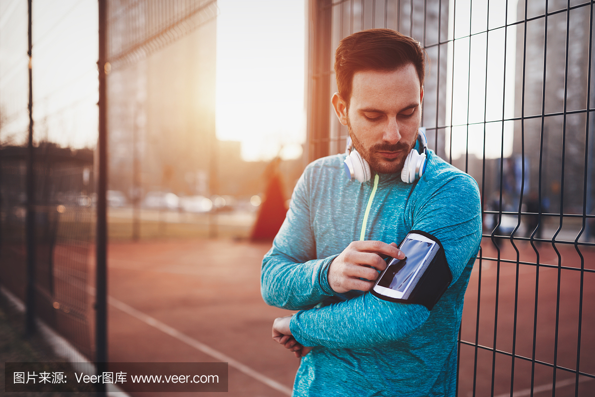 英俊健康的运动员在享受音乐时锻炼身体