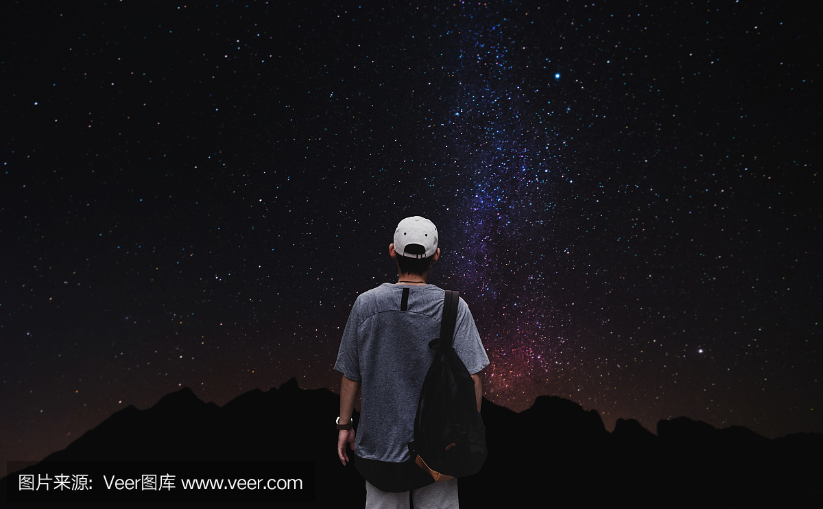 一个人背着背包站在夜晚的天空背景上五颜六色