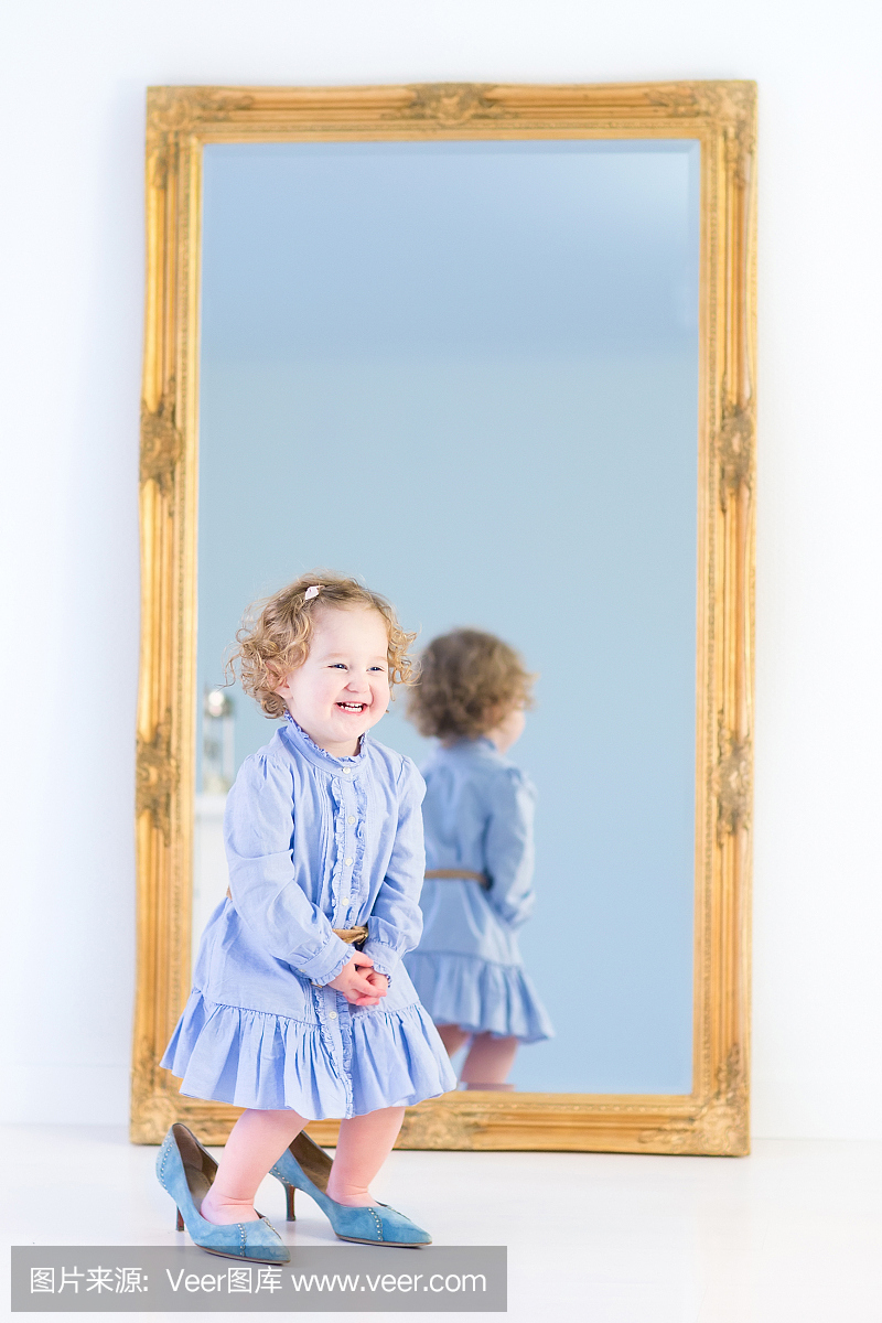 笑着蹒跚学步的女孩试穿她母亲的优雅高跟鞋